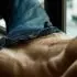 Torso de un hombre adulto recostado con los jeans abiertos y el pubis visible.
