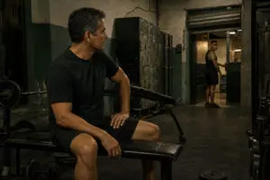 Hombre mexicano de cuarenta y cinco años mira a un joven tatuado al cierre de un gimnasio de barrio en Ciudad de México.
