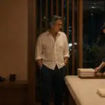 Arquitecto mexicano de 55 años y masajista tailandés adulto conversan junto a una camilla en un estudio nocturno de Bangkok.