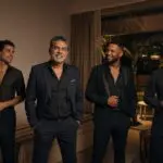 Hombre mexicano de 50 años posa en una suite de Playa del Carmen con tres bailarines adultos vestidos de negro.